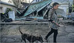  ?? VICTOR J. BLUE THE NEW YORK TIMES ?? LEFT: Elizabeth Parilla feeds her pets in front of her damaged home Wednesday in the Santurce neighborho­od of San Juan, Puerto Rico.