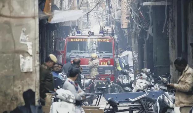  ?? PICTURE: MANISH SHARUP/AP ?? 0 An alleyway, tangled in electrical wire and too narrow for the fire engines forced the fire crew to try to extinguish the fire from 100m away