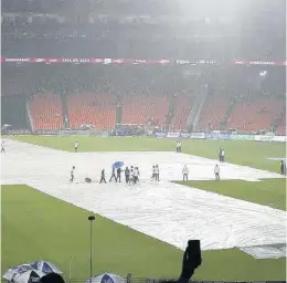  ?? AP ?? Groundsmen cover the pitch as it rains before the start of the Indian Premier League final between Chennai Super Kings and Gujarat Titans in Ahmedabad yesterday. The match was reschedule­d to be played today.