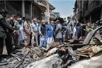  ??  ?? Pakistani officials visit the site where a jetliner crashed Friday in a residentia­l area in Karachi, killing 97 people on board. Only two people survived.