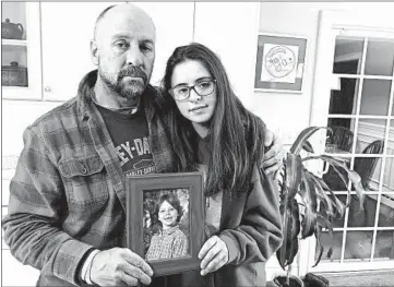  ?? DAVE COLLINS/AP ?? Mark Barden and daughter Natalie hold a photo of her brother, Daniel, at their home in Newtown, Connecticu­t.