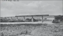  ?? RYCH MILLS COLLECTION ?? Smoke streams upwards in 1914 as a CPR westbound engine hauls five passenger cars and two baggage units across the Grand River in Galt.