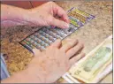  ?? Charles Krupa The Associated Press ?? A woman scratches an instant ticket in Methuen, Mass. The pandemic has been a rollercoas­ter for state lotteries.