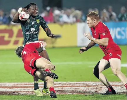  ?? / KARIM SAHIB / AFP ?? Seabelo Senatla of South Africa is tackled by Lucas Hammond of Canada as his teammate Connor Braid approaches during the Men's Sevens World Rugby Dubai Series.
