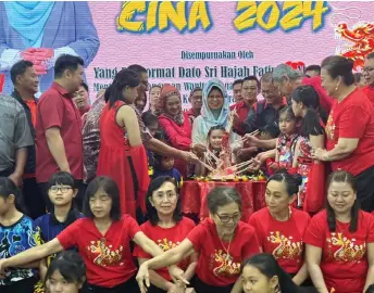  ?? ?? Fatimah, surrounded by officials and guests, joins them in the traditiona­l ‘Yee Sang Toss’ during the ‘Sejambak Kasih CNY 2024’ programme in Dalat.