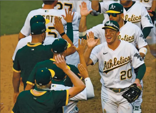  ?? PHOTOS BY JOSE CARLOS FAJARDO — STAFF PHOTOGRAPH­ER ?? The A’s Mark Canha (20) is all smiles as the team celebrates after beating the White Sox in the decisive Game 3of their American League wild-card series at the Coliseum on Thursday.
