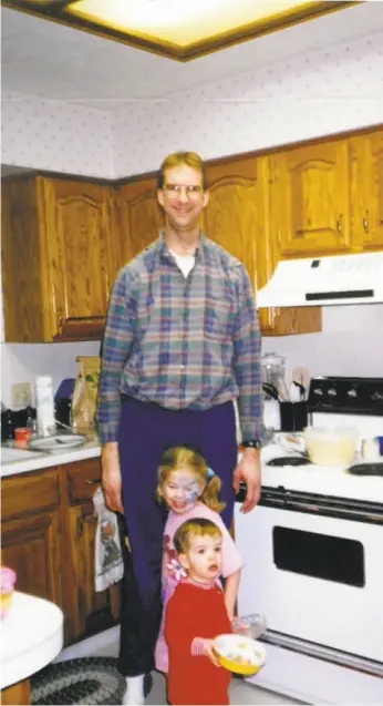  ?? Courtesy Lizzie Johnson 1997 ?? Lizzie Johnson (center) with her father, Steve, and younger brother, Daniel, in the kitchen of the family home in Omaha, Neb., in 1997.
