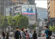  ?? JEAN CHUNG / BLOOMBERG ?? Commuters walk near a large screen featuring a broadcast of South Korean President Moon Jae-in and North Korean leader Kim Jong Un in Seoul, South Korea, on April 27.