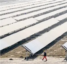  ?? ?? A worker walking past rows of solar panels at the Adani Group owned Khavda Renewable Energy Park in Khavda.