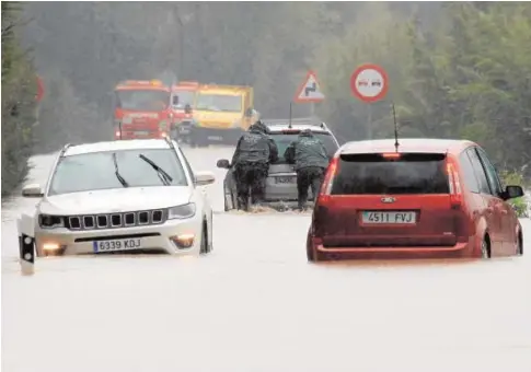  ?? FOTOS: EFE/A.CARRASCO RAGEL ?? La Guardia Civil ayuda a sacar los coches en la carretera A-2102 en San Roque