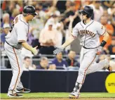  ?? Gregory Bull / Associated Press ?? Buster Posey is greeted by third-base coach Phil Nevin after his solo homer in the seventh.