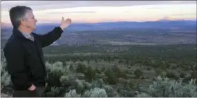  ?? GILLIAN FLACCUS — THE ASSOCIATED PRESS ?? Joe Krenowicz, executive director of the Madras-Jefferson County Chamber of Commerce, gestures toward Mt. Jefferson as the sun rises over Madras, Ore. The first place to experience total darkness as the moon passes between the sun and the Earth will be...