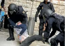  ??  ?? Spanish police scuffle with a man outside a polling station in Tarragona for the banned independen­ce referendum.