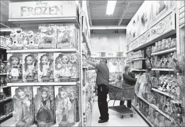  ?? Photograph­s by Anne Cusack
Los Angeles Times ?? “FROZEN” was such a hit at Toys R Us that the company expanded its selection from a few dozen products in the beginning of 2014 to more than 300 during the holidays. Above, shoppers peruse merchandis­e last month.