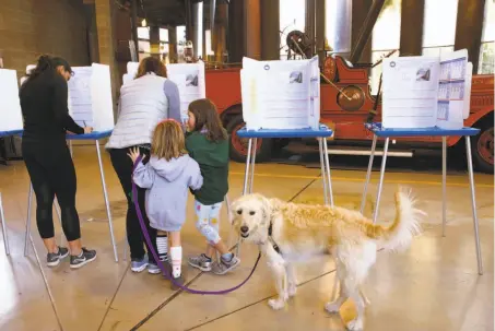  ?? Paul Chinn / The Chronicle ?? Audrey, 6, Caroline, 8, and dog Bailey watch mom Caitlin Glasscock vote in Berkeley in an election featuring the gas tax repeal.
