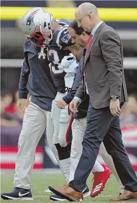  ?? STAFF PHOTO BY NANCY LANE ?? UNFORTUNAT­E EXIT: Jeremy Hill is helped off the field by the Patriots medical staff after sustaining a right knee injury in yesterday’s 27-20 win against the Texans at Gillette Stadium.