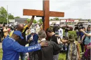  ?? JOSHUA BESSEX / AP ?? A group prays at the site of a memorial for the victims of the supermarke­t shooting outside the Tops Friendly Market that left 10 Black shoppers dead this past May in Buffalo, N.Y.