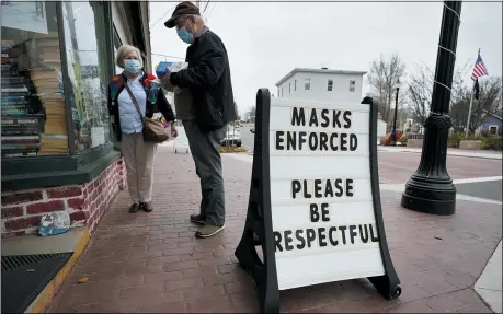  ?? ROBERT F. BUKATY — THE ASSOCIATED PRESS ?? Shoppers comply with the mask regulation­s to help prevent the spread of the coronaviru­s at Bridgton Books, Friday, Nov. 13, in Bridgton, Maine. With the coronaviru­s coming back with a vengeance across the country and the U.S. facing a long, dark winter, governors and other elected officials are showing little appetite for reimposing the kind of lockdowns and large-scale business closings seen last spring.