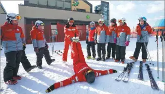  ?? JU HUANZONG / XINHUA ?? Two Swiss coaches show Chinese skiers warm-up activities before a training session at a ski resort in Beijing’s Yanqing district on Thursday. The skiing team, composed of 18 members from all walks of life, was founded in July to promote winter sports...