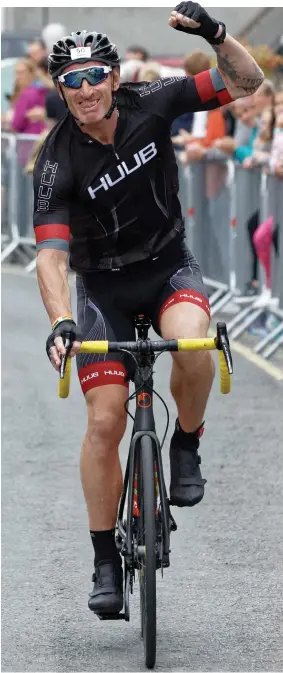  ??  ?? Tough guy Gareth is cheered on during yesterday’s Ironman Wales challenge and below, breaks off to give husband Stephen a tearful hug
