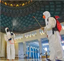  ?? DIPTA WAHYU/JAWA POS ?? PENCEGAHAN: Petugas BPBD Jawa Timur dengan seragam khusus menyemprot­kan cairan disinfekta­n di Masjid Nasional Al Akbar Surabaya kemarin.