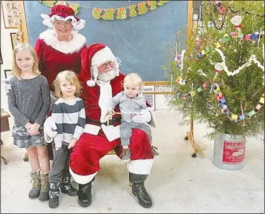  ?? (NWA Democrat-Gazette/Susan Holland) ?? Santa and Mrs. Claus visit with children Dec. 4 at the Gravette Historical Museum annex after the Christmas parade. Here they are pictured with Calliope, 8; Jasper, 5; and Nico, 1, children of Christi and Jeff Prowers, of Gravette. The nearby Christmas tree is decorated in keeping with the “An Old-Fashioned Christmas” theme.