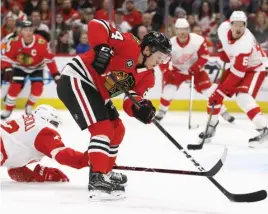  ?? JONATHAN DANIEL/GETTY IMAGES ?? The Red Wings’ Andreas Athanasiou dives in an effort to deflect a shot by Hawks center Dominik Kahun on Sunday at the United Center.