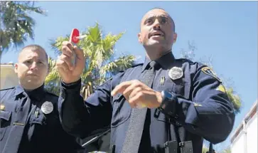  ?? David Brooks San Diego Union-Tribune ?? OFFICER EMILIO Ramirez demonstrat­es the San Diego Police Department’s new drug-detection devices. The two machines analyze mouth swabs provided by drivers to detect substances including pot and opiates.