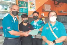  ?? ?? Philip (left) receives a Socso registrati­on form from a coffee-shop worker during the inspection on Jakar Bazaar. At right is Lim.