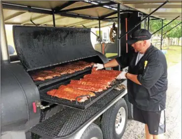  ?? CHAD FELTON — THE NEWS-HERALD ?? Pitmaster Devan Stewart prepares fare for FarmFest on July 7. This year, ribs, beer and additional live music are featured at the expanded event. FarmFest runs July 7 - 9.