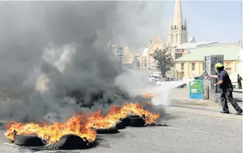  ?? Picture: ALAN EASON ?? DAMAGE CONTROL: Firefighte­rs extinguish burning tyres set alight by protesting Samwu workers in Buffalo Street on Tuesday. Workers also disrupted the city centre, trashing bins.