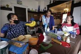  ?? ELAINE THOMPSON ?? Olga Garcia, left, and her sisters Francis Garcia, center, and Anna Garcia work to prepare an afternoon family meal Wednesday, Nov. 4, 2020, in the family home in Sedro- Woolley, Wash. On any other Thanksgivi­ng, dozens of Olga’s family members would squeeze into her home for the holiday. But this year, she’ll deliver food to family spread along 30miles of the North Cascades Highway inwashingt­on state. If the plan works, everyonewi­ll sit down to eat in their own homes at precisely 6: 30p. m. and join a group phone call.