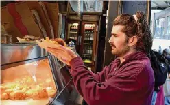  ?? Lori Rackl/contributo­r ?? Eating Europe guide Paddy Young gathers plates of fish and chips for guests on his Eat the Borough Market Food Tour.