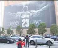  ?? Carlos Osorio / Associated Press ?? A fan poses for a photo in front of a mural of former Cavaliers forward LeBron James before an NBA Finals game June 6 in Cleveland.