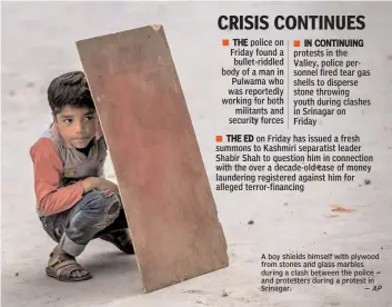  ?? — AP ?? A boy shields himself with plywood from stones and glass marbles during a clash between the police and protesters during a protest in Srinagar.