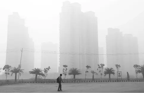  ??  ?? A man walks through smog near Delhi, India. — Reuters photo