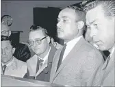  ?? THE ASSOCIATED PRESS ?? Khalil Islam, center, is booked as the third suspect in the slaying of Malcolm X in New York.