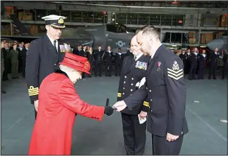  ??  ?? Britain’s Queen Elizabeth II presents the 15 years long service and good conduct medal to Petty Officer Matthew Ready, during a visit to the HMS Queen Elizabeth at HM Naval Base, ahead of the ship’s maiden deployment, in Portsmouth, England, Saturday May 22, 2021. HMS Queen Elizabeth will be leading a 28-week deployment to the Far East that Prime Minister Boris Johnson has insisted is not confrontat­ional towards China. (AP)