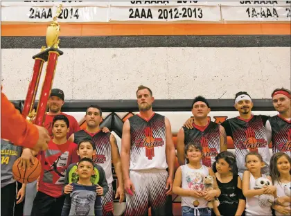  ?? Morgan Timms/The Taos News ?? Team Flavio’s Paving is awarded the first-place trophy from Gilbert Atencio on Sunday (March 31) after their victory against Team Nuevos at Taos High School. Dominick Baca is pictured at the far right wearing a red headband.