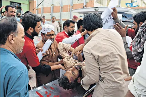  ??  ?? An injured man is brought to a hospital following a bomb blast that killed more than 128 people at an election rally in Baluchista­n province, the third bomb attack this week