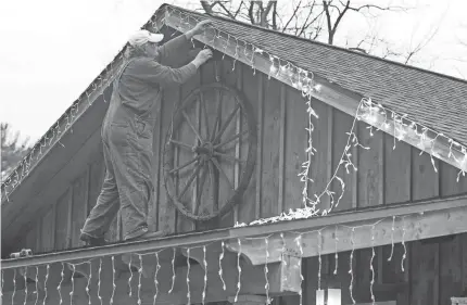  ?? JACQUELINE DORMER/REPUBLICAN-HERALD VIA AP ?? Brian Tassone of Pottsville, Pa., hangs lights around the roof on The Arts Barn in Schuylkill Haven, Pa., on Sunday.
