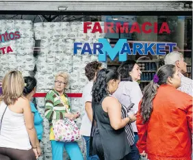  ?? FEDERICO PARRA/AFP/Getty Images files ?? People queue up at a pharmacy in Caracas in January. Lineups for food are the norm now.