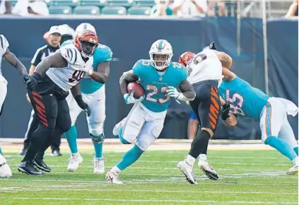  ?? BRYAN WOOLSTON/AP ?? Dolphins running back Gerrid Doaks (23) runs against the Bengals in the second half of Sunday’s exhibition game in Cincinnati.