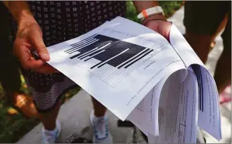  ?? Jim Rassol / Associated Press ?? Journalist­s gather outside the Paul S. Rogers Federal Building and U.S. Courthouse in downtown West Palm Beach, Fla., to read a heavily blackout document released by The Justice Department on Friday.