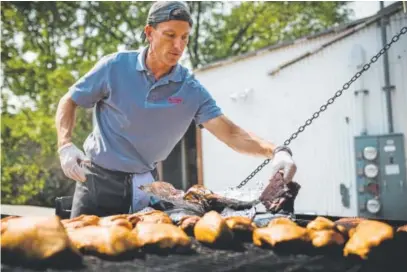  ?? Photos by Gabriel Scarlett, The Denver Post ?? Jeff Kennedy, one of the three founders and owners of Moe’s Original Bar B Que, prepares chicken and ribs on a woodburnin­g smoker outside their flagship restaurant in Eagle last month.