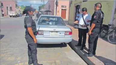  ??  ?? Un conductor recibe una multa de la Policía Municipal de Valladolid, donde los autos son estacionad­os en las esquinas o en franjas amarillas