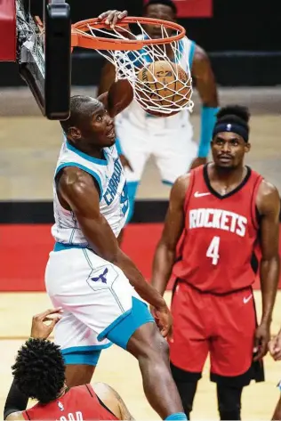  ?? Mark Mulligan / Staff photograph­er ?? Hornets center Bismack Biyombo dunks over Christian Wood in the second quarter. After a close first half, the Hornets outscored the Rockets 35-15 in the third quarter en route to a blowout win.