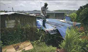  ?? Carlos Giusti Associated Press ?? A MAN checks his roof ahead of the 2020 hurricane season in Corozal, P.R. Global nonprofits often exclude the island because it is part of the U.S., and American nonprofits often exclude it because it’s not a state.