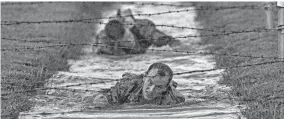  ?? JOHN BAZEMORE/AP ?? U.S. Army Capt. Michael Rose, of the 101th Airborne, front, and teammate Capt. John Bergman crawl under barbed wire while competing for the title of Best Ranger.