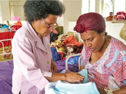  ?? Photo: ABC ?? A nurse helps Julie settle her new son, Isaac. Julie says providing for her six kids is a struggle, but she can rely on subsistenc­e farming to feed them.